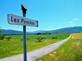 A road sign in France with a road in the background and lots of very green countryside