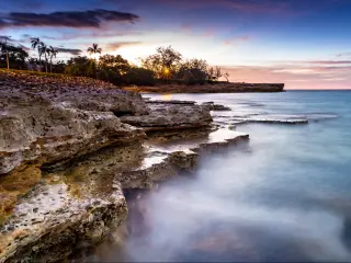 Darwin, NT, Australia taken as a night cliff Sunset with rocks and sea in the foreground, and trees in the distance.