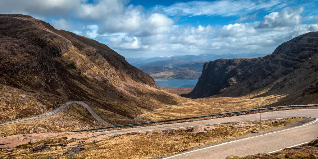 The twisty road of Bealach na Ba, Scotland, with a loch in the distance