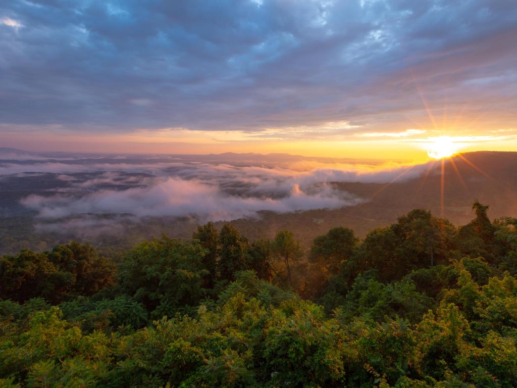 Morning sun rays through clouds and fog over mountains at Arkansas Grand Canyon Scenic Overlook