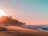 Malibu Beach, California, USA with a sunset along the beach and cliffs.