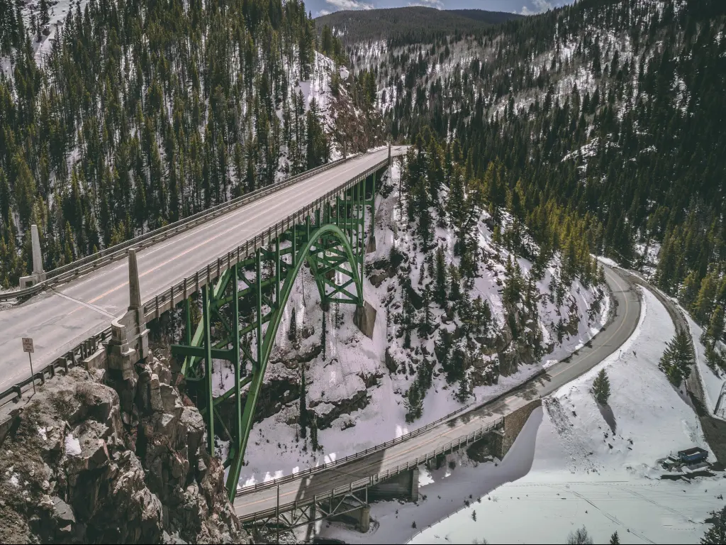 Aerial photo of the Red Cliff Bridge on Tennessee Pass in the Mountains of Colorado in the winter, with snow and frozen Eagle River below.