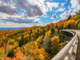 Trees with red and gold foliage cover mountain slopes which stretch out into the distanc
