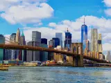 A scenic view of Brooklyn Bridge above the East River with the Manhattan skyline on a cloudy day