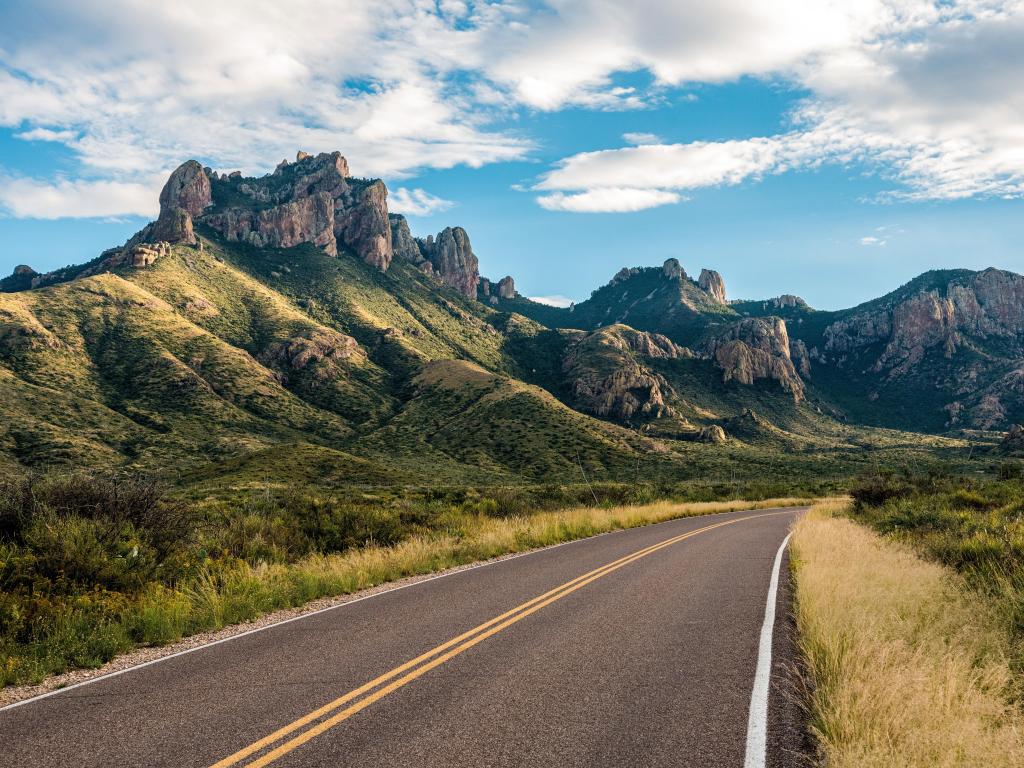 Road with steep mountain cliffs rising up 