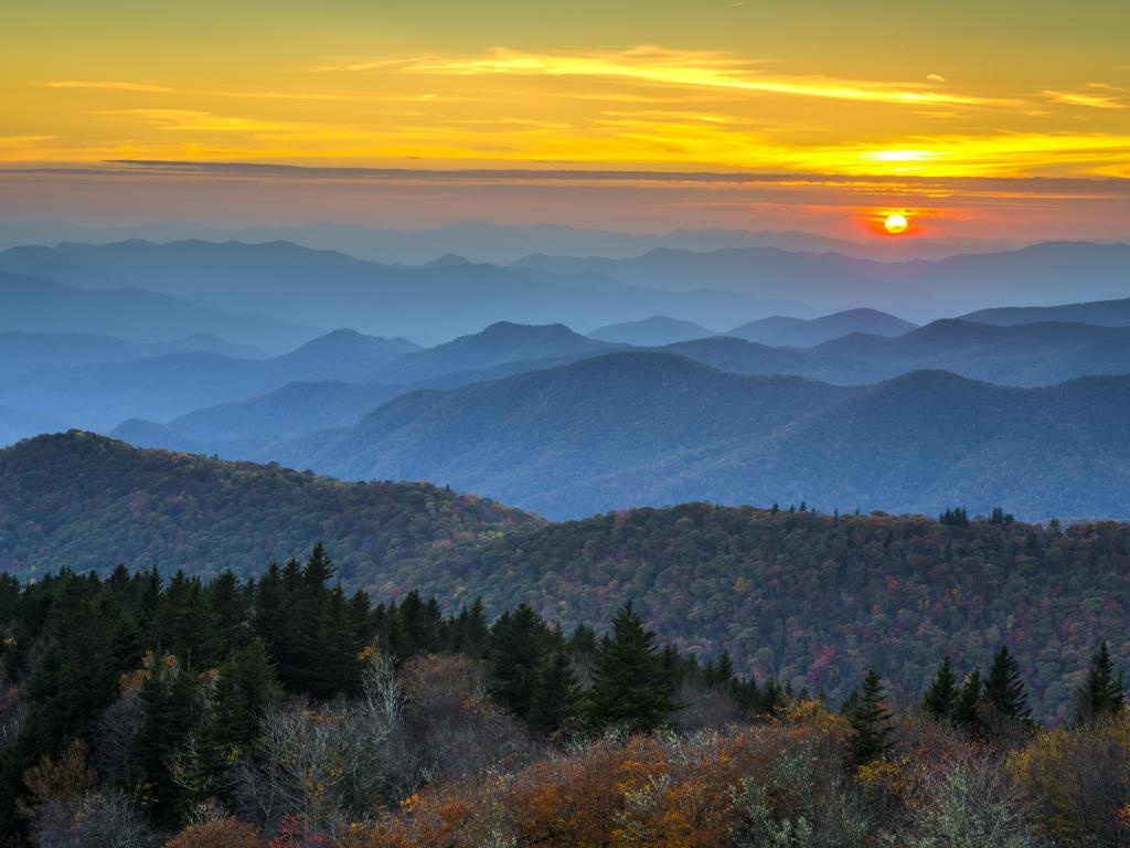 Sunset view over forested mountains with hazy blue light and fall foliage