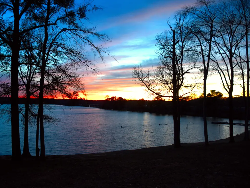 A beautiful golden orange sunset in Lake Oconee with trees surrounding the water