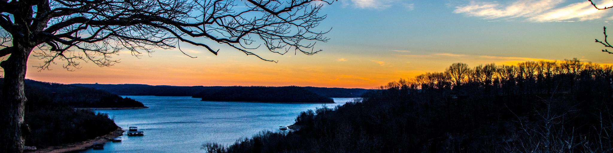 Eureka springs sunset at lake with trees in the foreground