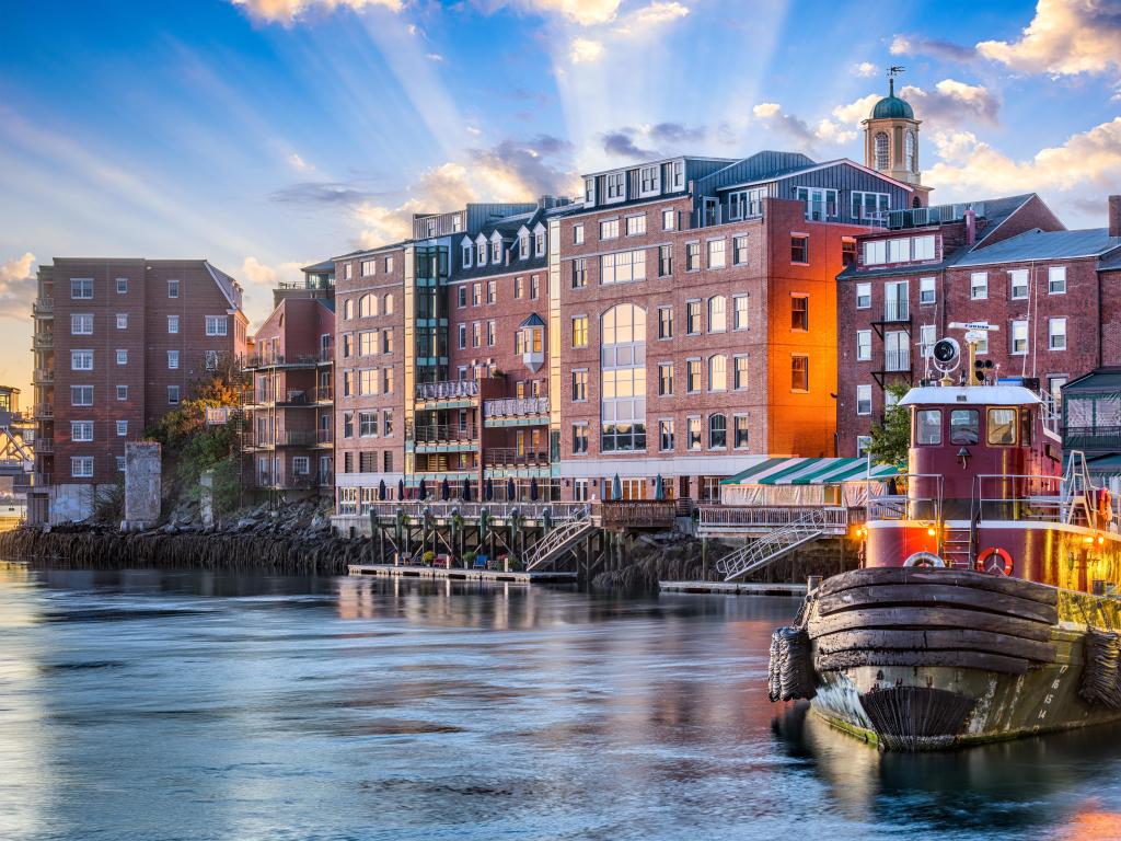 Portsmouth, New Hampshire, USA taken with the town cityscape in the background, a fishing boat in the foreground on the river and a sunny background.