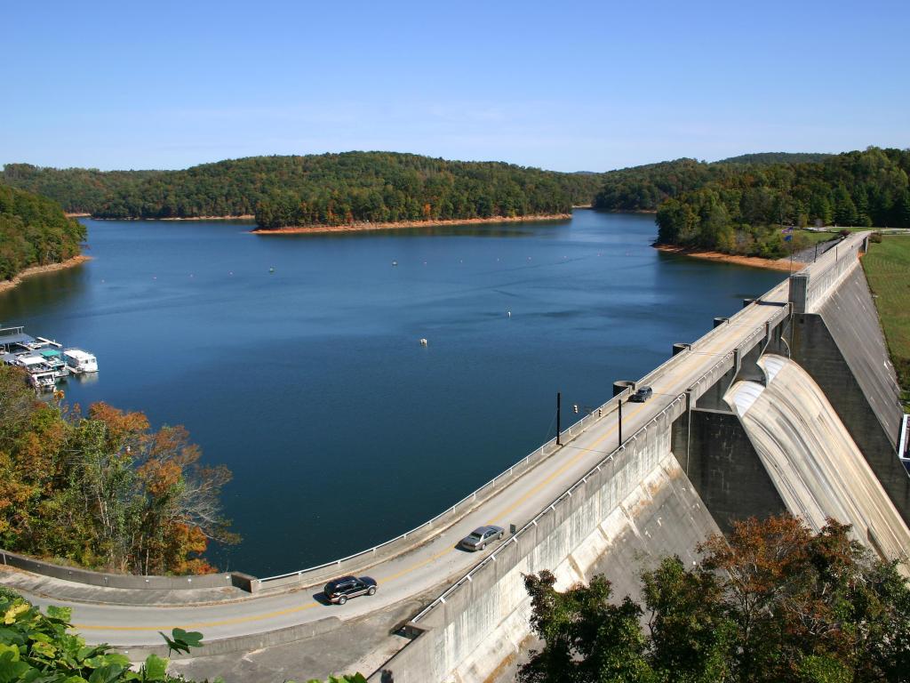 Cars driving along the road across Norris Dam in Tennessee, with boats moored in the background