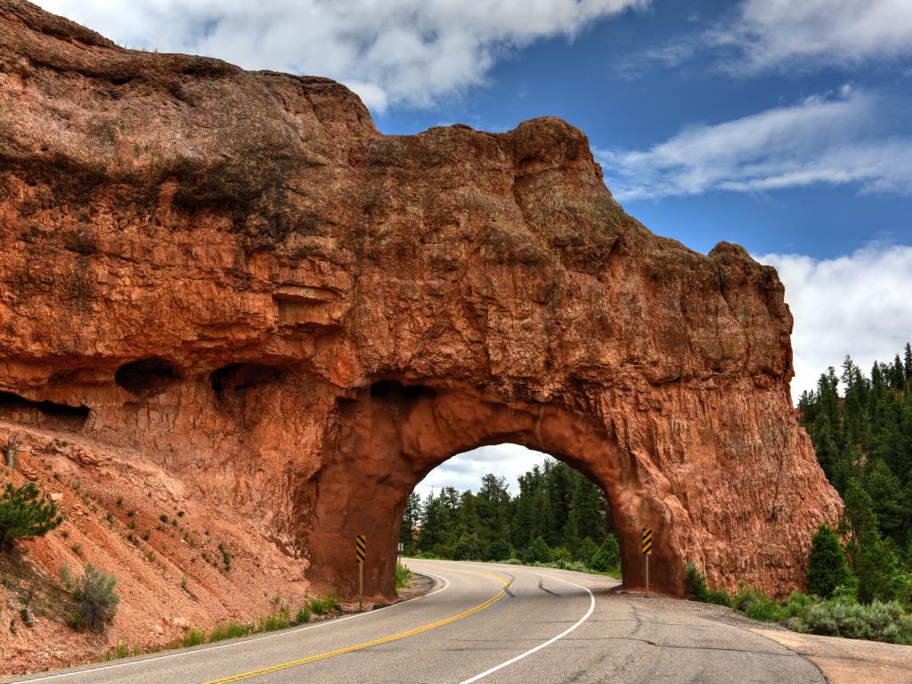 A natural red stone arch formation in the highway in Bryce Canyon National Park on a sunny morning