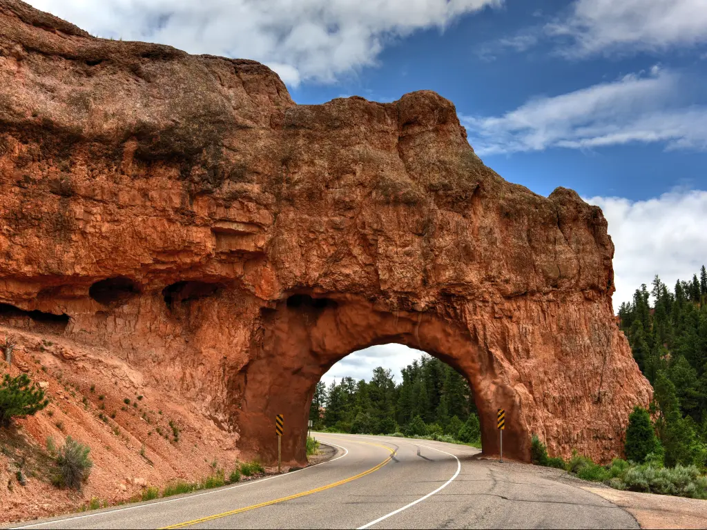 A natural red stone arch formation in the highway in Bryce Canyon National Park on a sunny morning