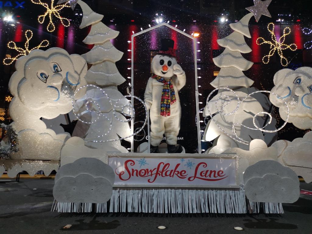 A Christmas parade in Bellevue with a snowman in a costume and white trees