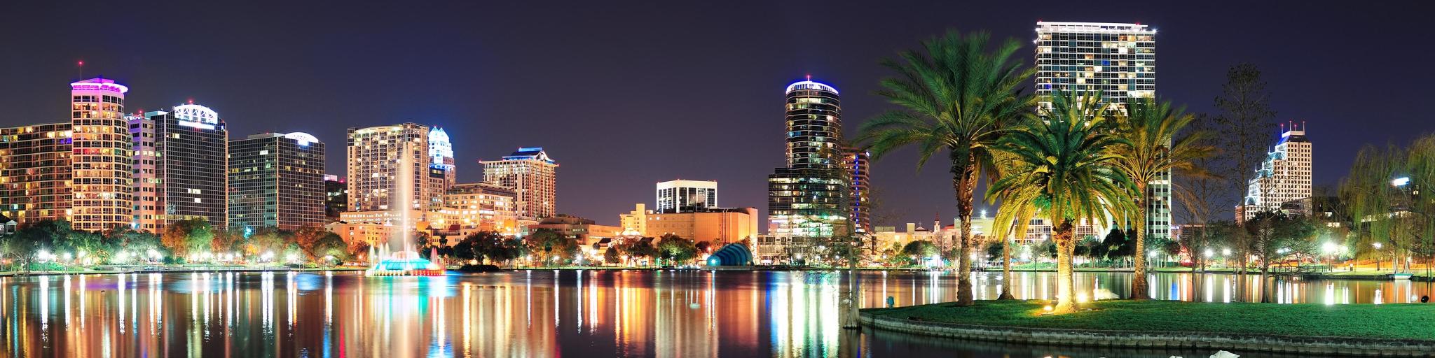 Orlando downtown skyline panorama over Lake Eola at night with urban skyscrapers and clear sky.