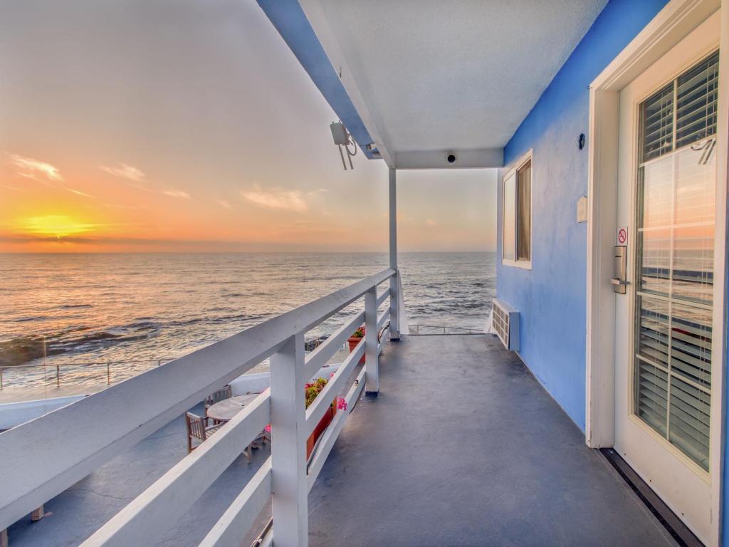Sun setting across the ocean alongside the bright blue rooms at The Inn at Sunset Cliffs, San Diego