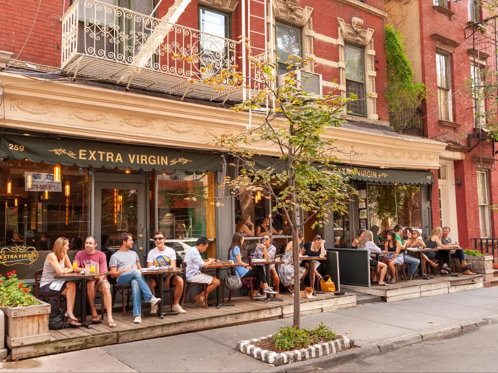 Diners seated along the pavement during late summer, outside Extra Virgin Restaurant in Greenwich Village