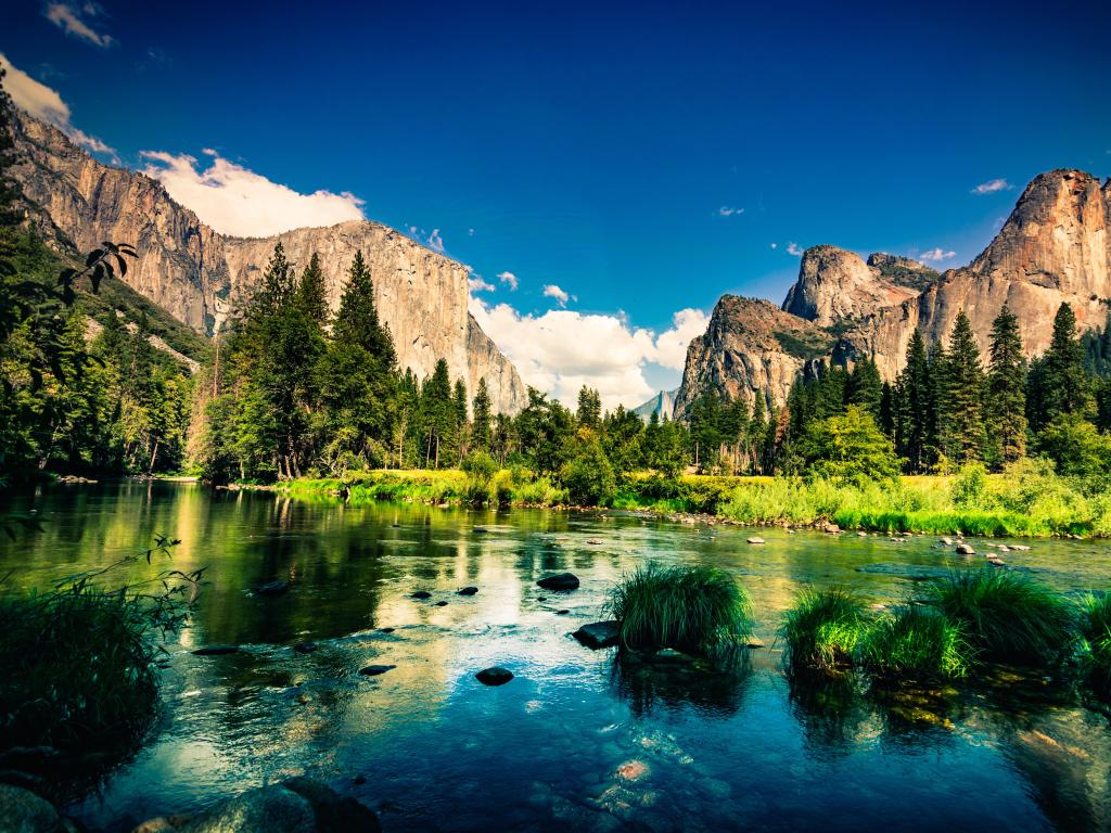 Yosemite National Park, California, USA with water in the foreground and the mountains against a blue sky.