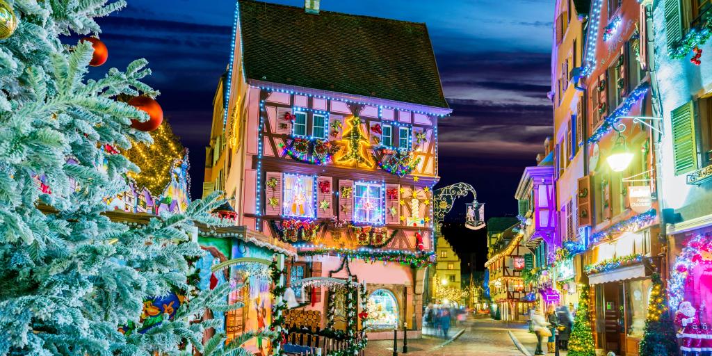 A street view of a decorated house in Colamar at Christmas with a Christmas tree in the foreground