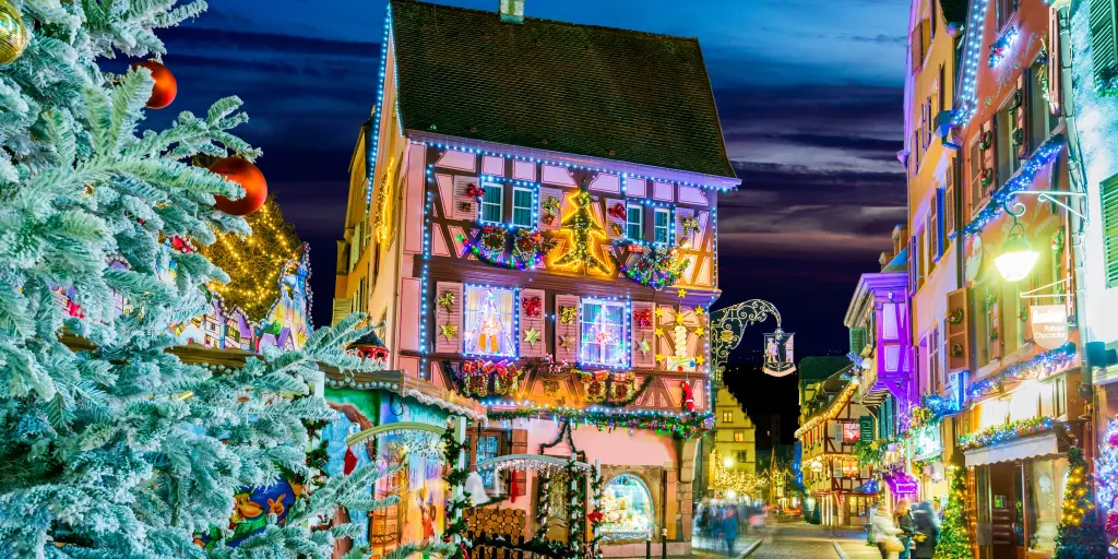 A street view of a decorated house in Colamar at Christmas with a Christmas tree in the foreground