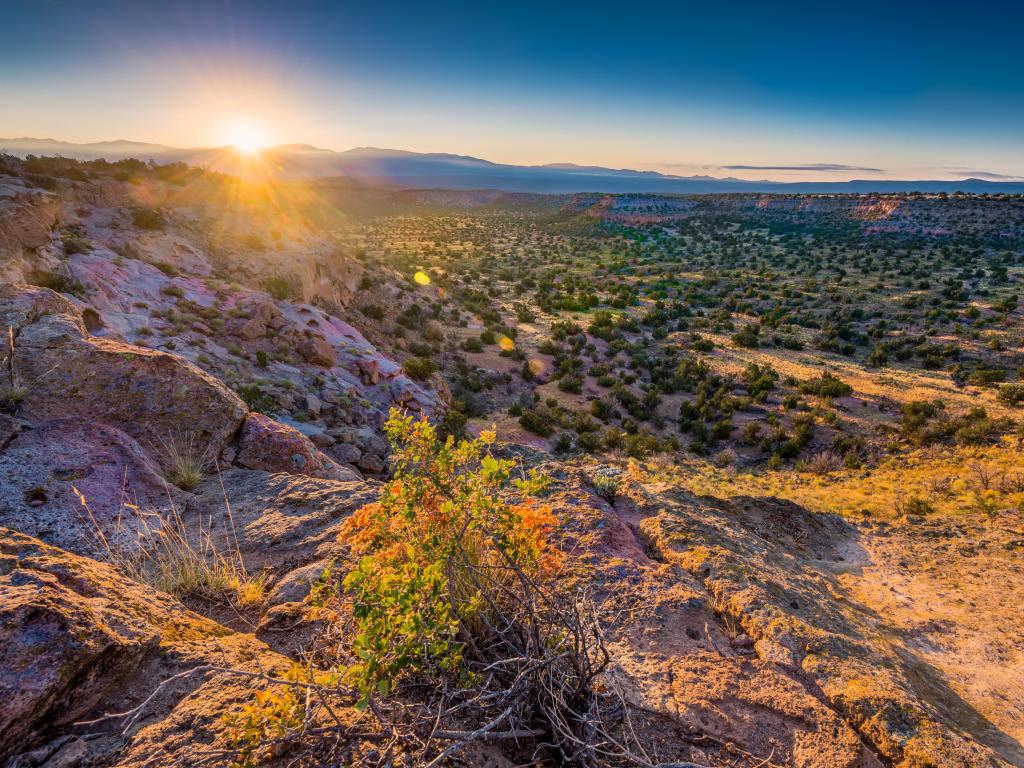 Bandelier National Monument, USA with a golden sunrise over the stunning landscape with rocks and trees in the distance. 