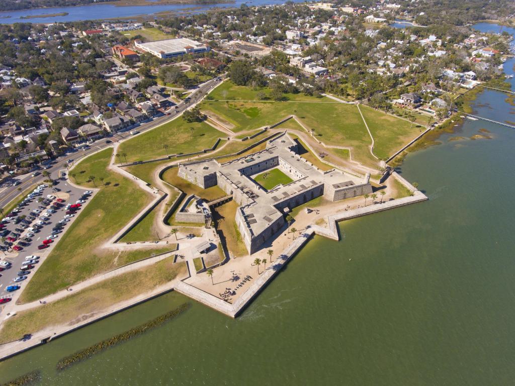 Aerial view of the star-shaped Castillo de San Marcos in St Augustine, Florida, at the water's edge, surrounded by grass