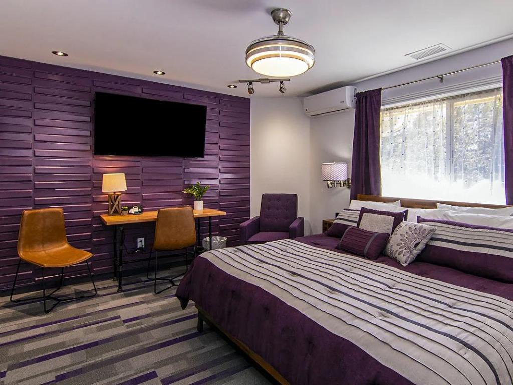 Purple themed bedroom at 303 BnB Flagstaff, with large bed, desk area and mounted wide-screen TV