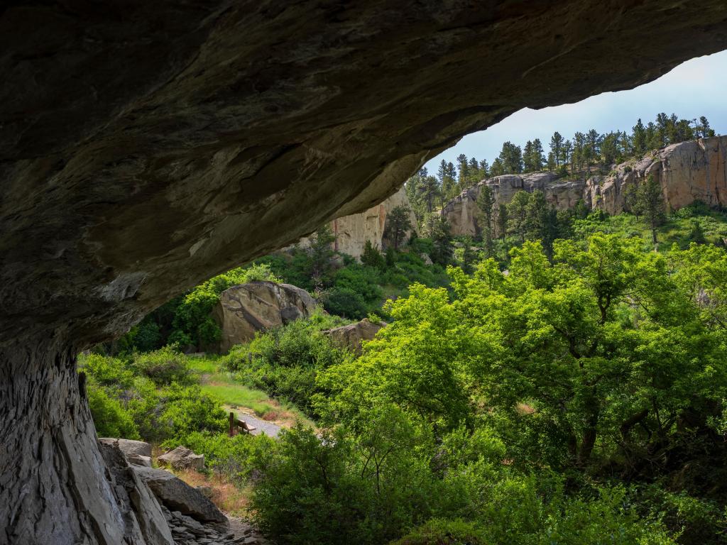 Pictograph Cave, Montana, USA with rocks overlooking trees and cliffs on a sunny day.