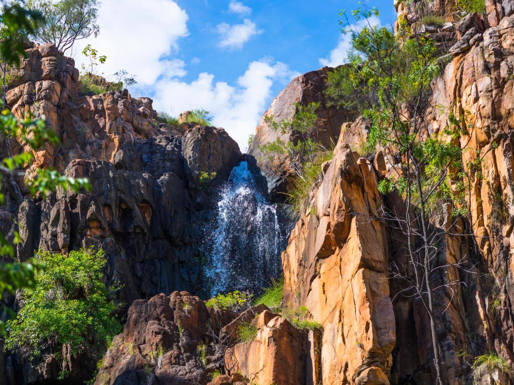 Nitmiluk (Katherine Gorge) National Park, Katherine, Australia with an impressive waterfalls and tall rock cliffs between on a sunny day.