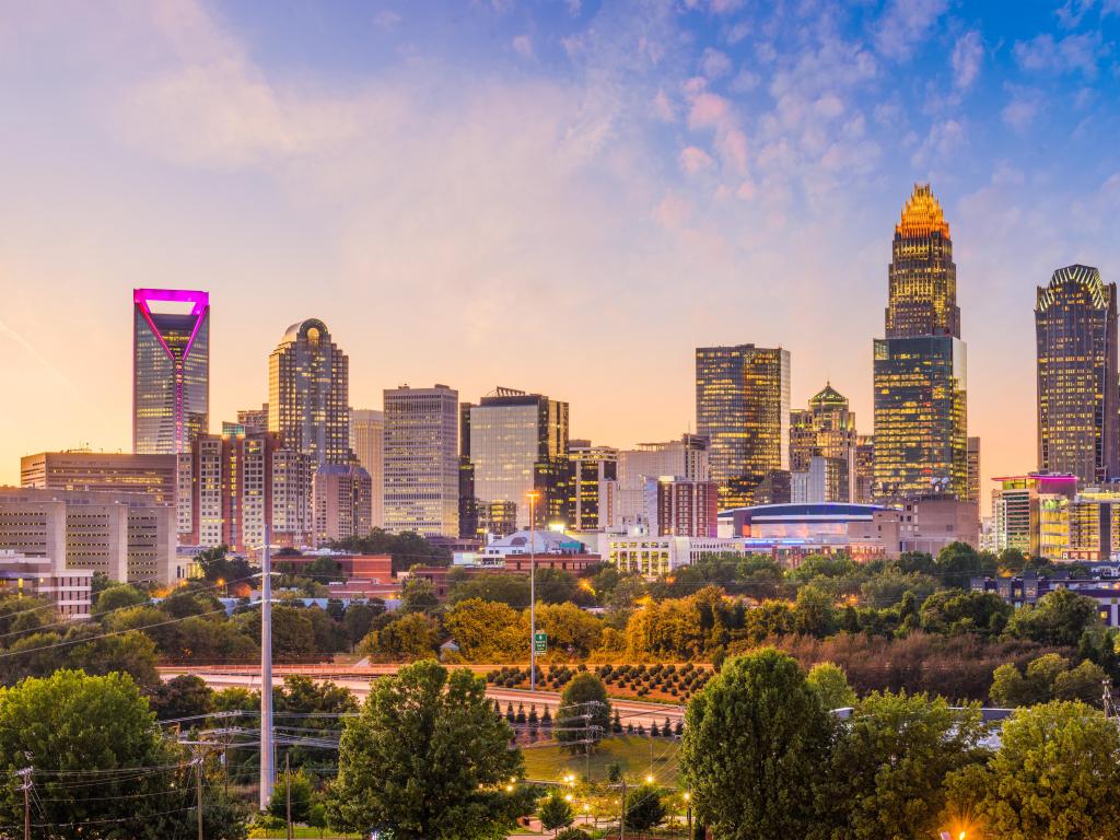 Charlotte, North Carolina, USA with the downtown skyline at dusk, trees in the foreground and a beautiful sky. 