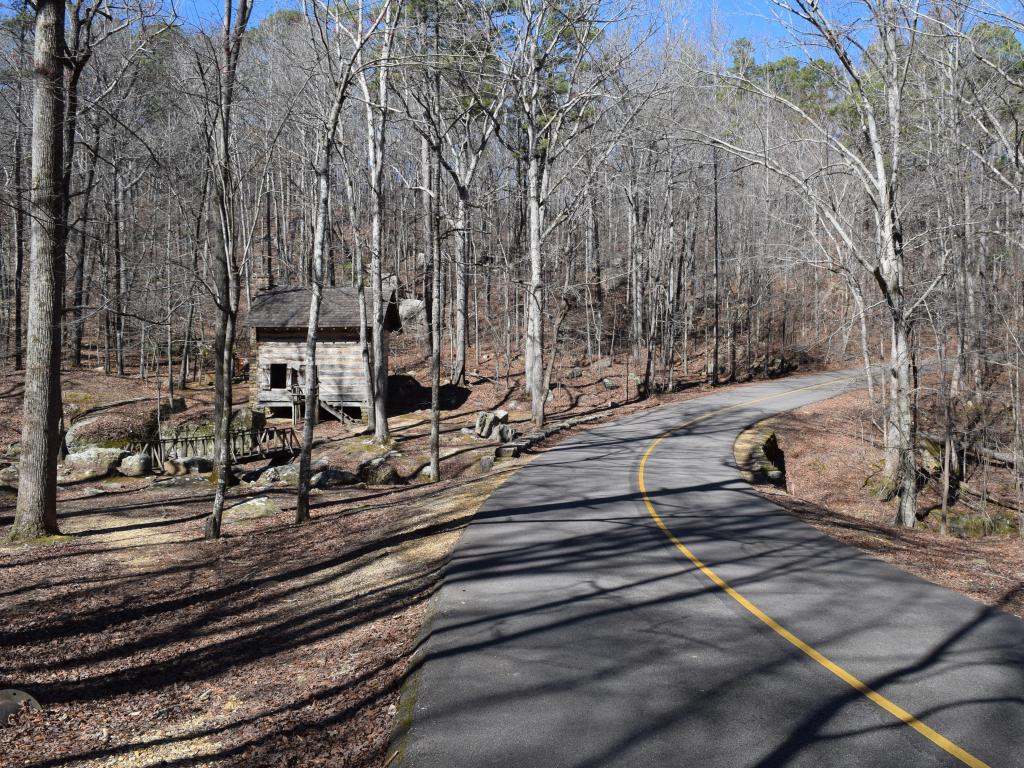 Road running through Tishomingo State Park, with bare winter trees either side and an old barn beside the road