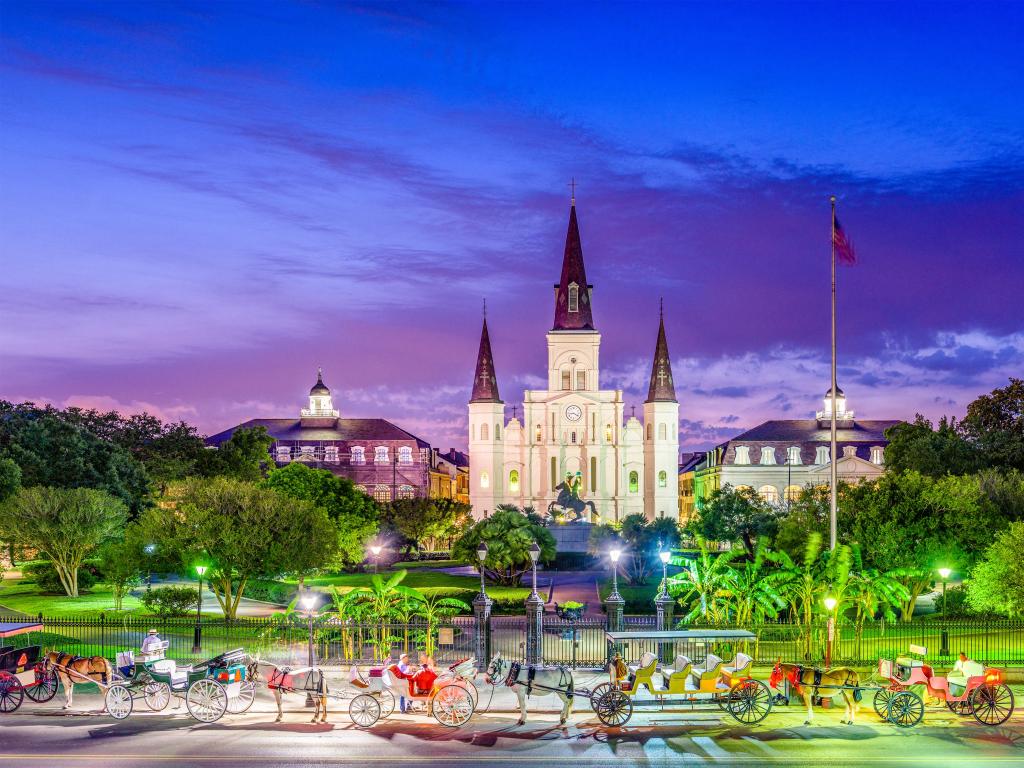 New Orleans, Louisiana with horses and carts waiting outside St. Louis Cathedral and Jackson Square at night.