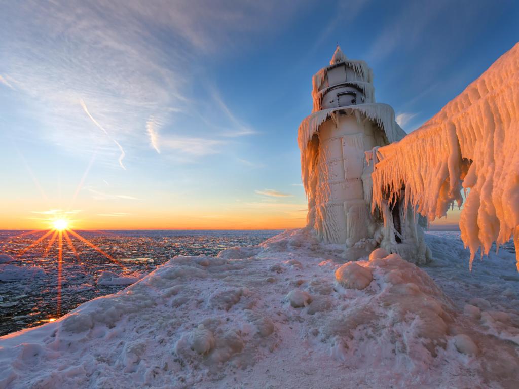 A winter sunset over Lake Michigan casts its glow on the ice-shrouded St. Joseph northern pier