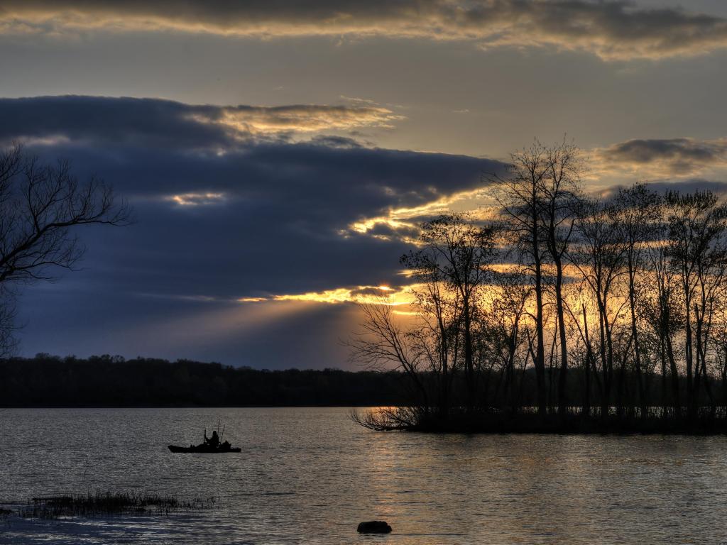 Cesear Creek State Park, Ohio, USA taken at Sunset with the lake in the foreground and trees in the background as silhouettes against the sky.