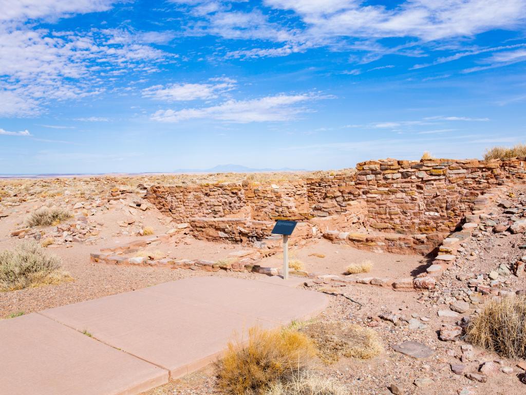 Indian ruins and signposting at Homolovi State Park, with blue skies against desert landscape