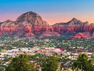 Ariel view of downtown Sedona cityscape with mountains in the background as the sun sets 