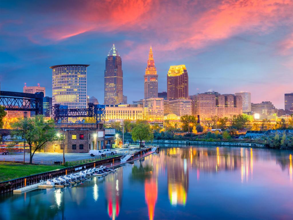 Cleveland, Ohio with Cuyahoga River in the foreground and the city skyline in the background reflecting in the water at night with a red sky.