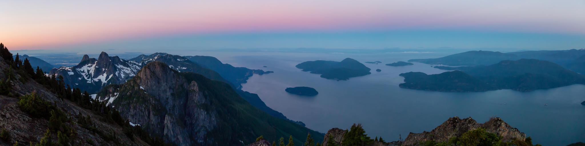Panoramic view of Howe Sound, North of Vancouver, taken at sunset from the top of a mountain with a little snow remaining, showing the ocean and small islands