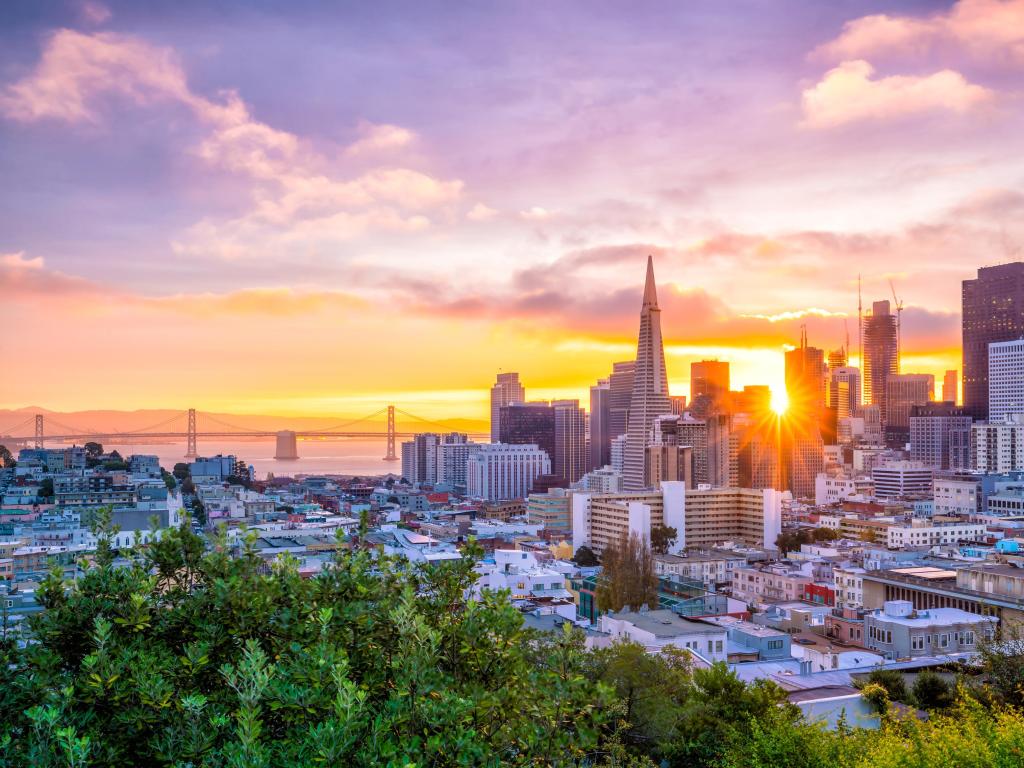 San Francisco, USA with a beautiful view of the business center in downtown San Francisco at sunset with the iconic bridge in the distance.