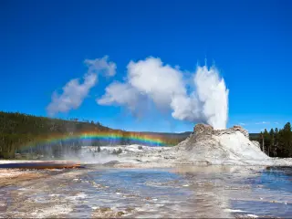 Rainbow near Castle geyser on a clear day, Yellowstone National Park, Wyoming, USA.