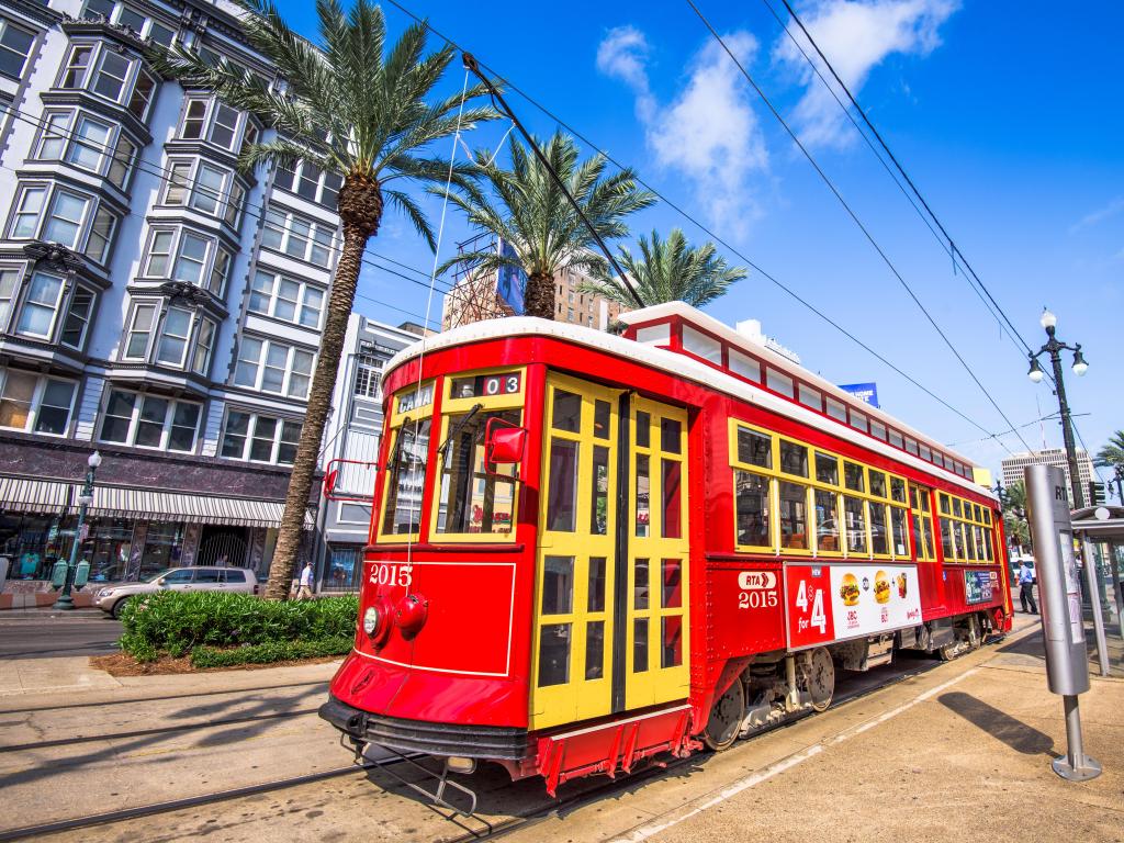 New Orleans, Louisiana, USA with a streetcar in downtown New Orleans on Canal Street on a sunny day with buildings in the background.