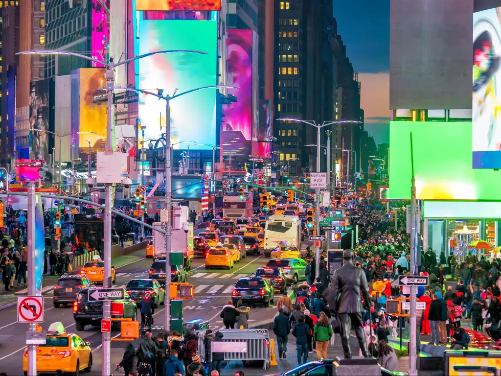 Times Square with neon art and shops, and crowds bustling along the streets during twilight