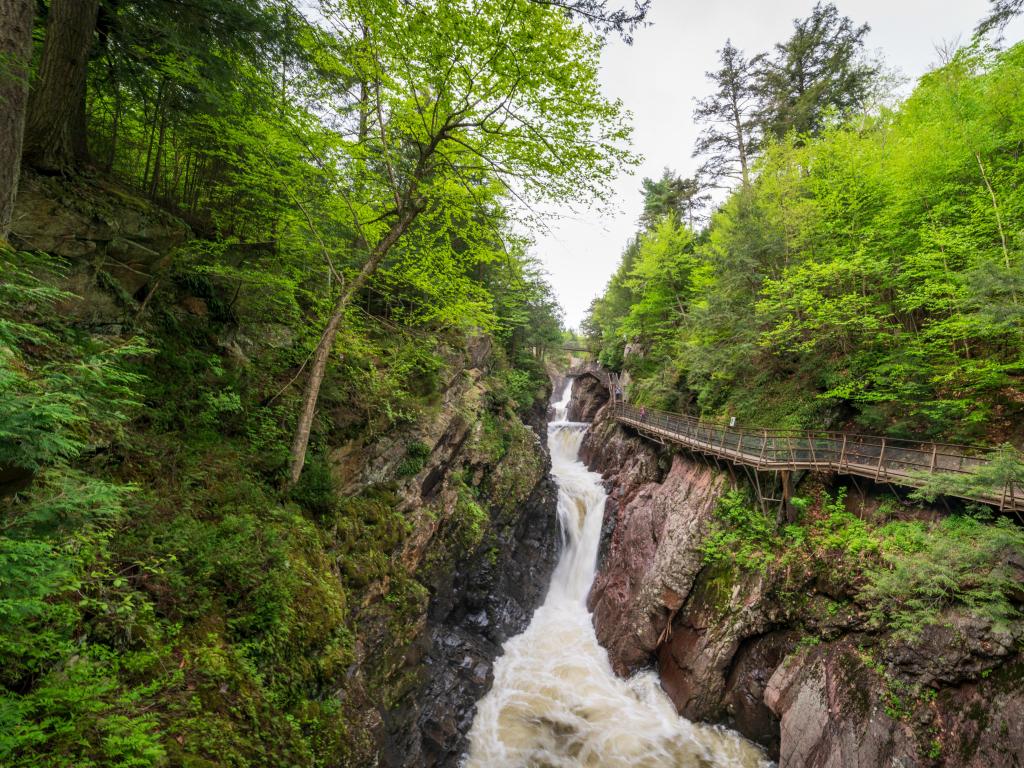High Falls Gorge, NY, USA with  trees either side and a bridge leading to the waterfall.