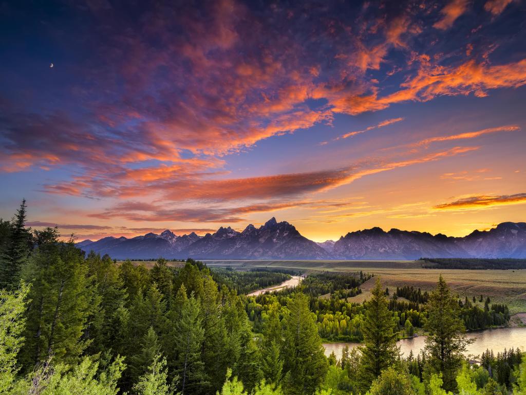 Snake River, Grand Teton National Park, Wyoming, USA taken with a colorful sunset, trees in the foreground and mountains in the distance. 