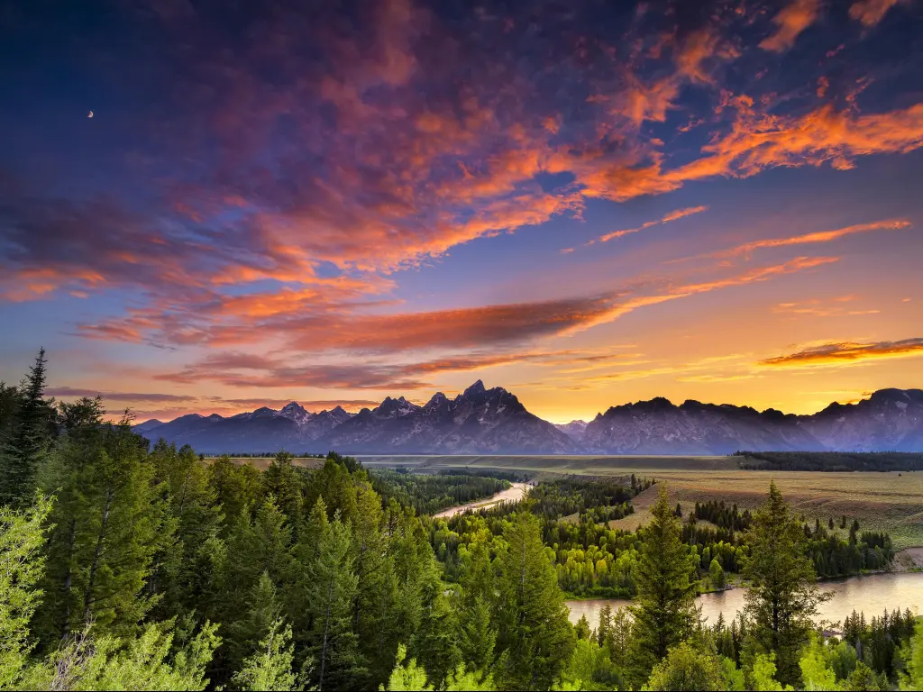 Snake River, Grand Teton National Park, Wyoming, USA taken with a colorful sunset, trees in the foreground and mountains in the distance. 