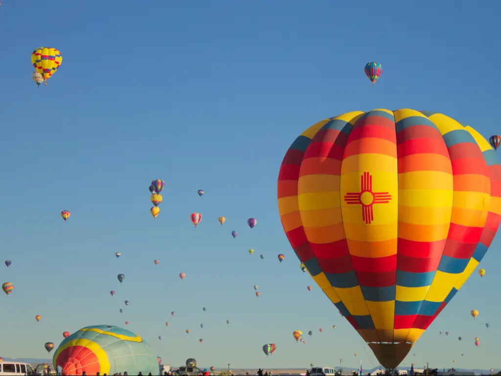 Large hot air ballon with zia sun symbol. Many hot air balloons in background. Albuquerque International Balloon Fiesta - Albuquerque, NM, USA.