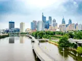 View of Philadelphia Skyline during daytime, with skyscrapers in background, river and greenery in foreground