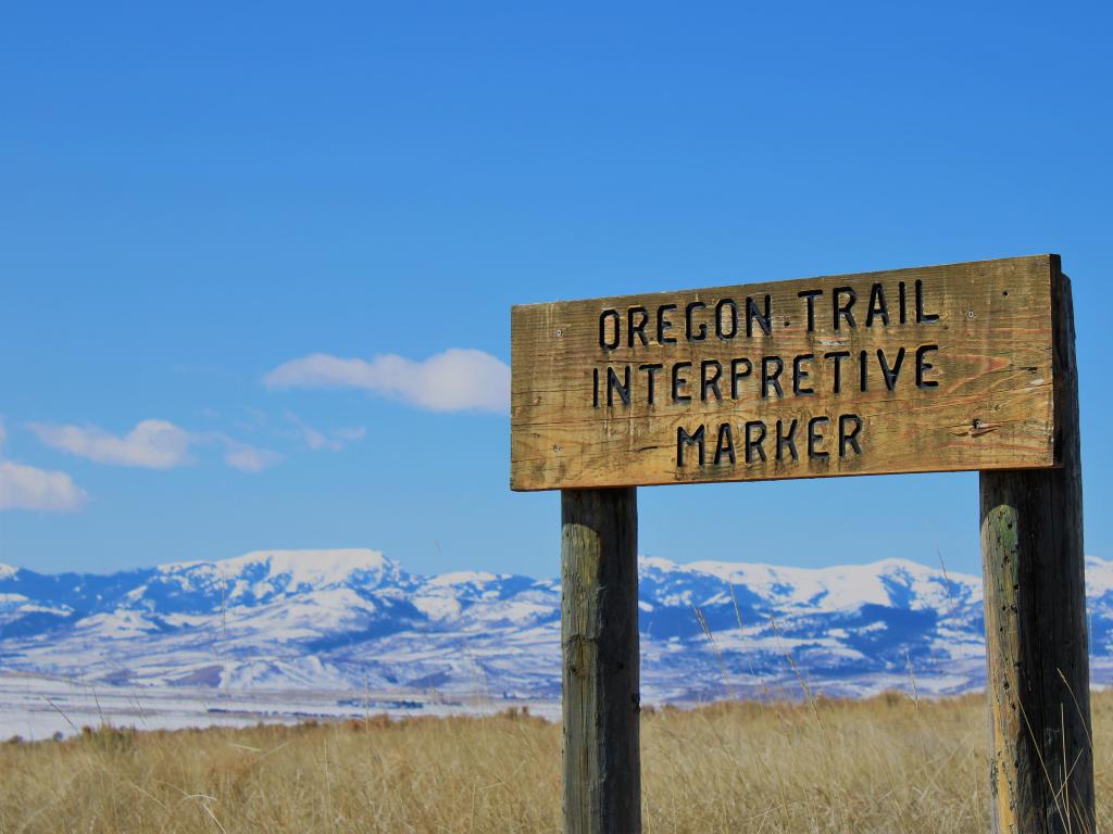 Historical Oregon Trail wooden signpost with mountains in the background