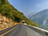 Empty winding Big Oak Flat Road, with tunnel ahead carved into hillside, with forests and valleys surrounding