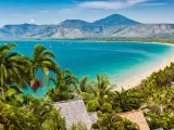 View of the blue ocean and beautiful sandy beach, palm trees in the foreground