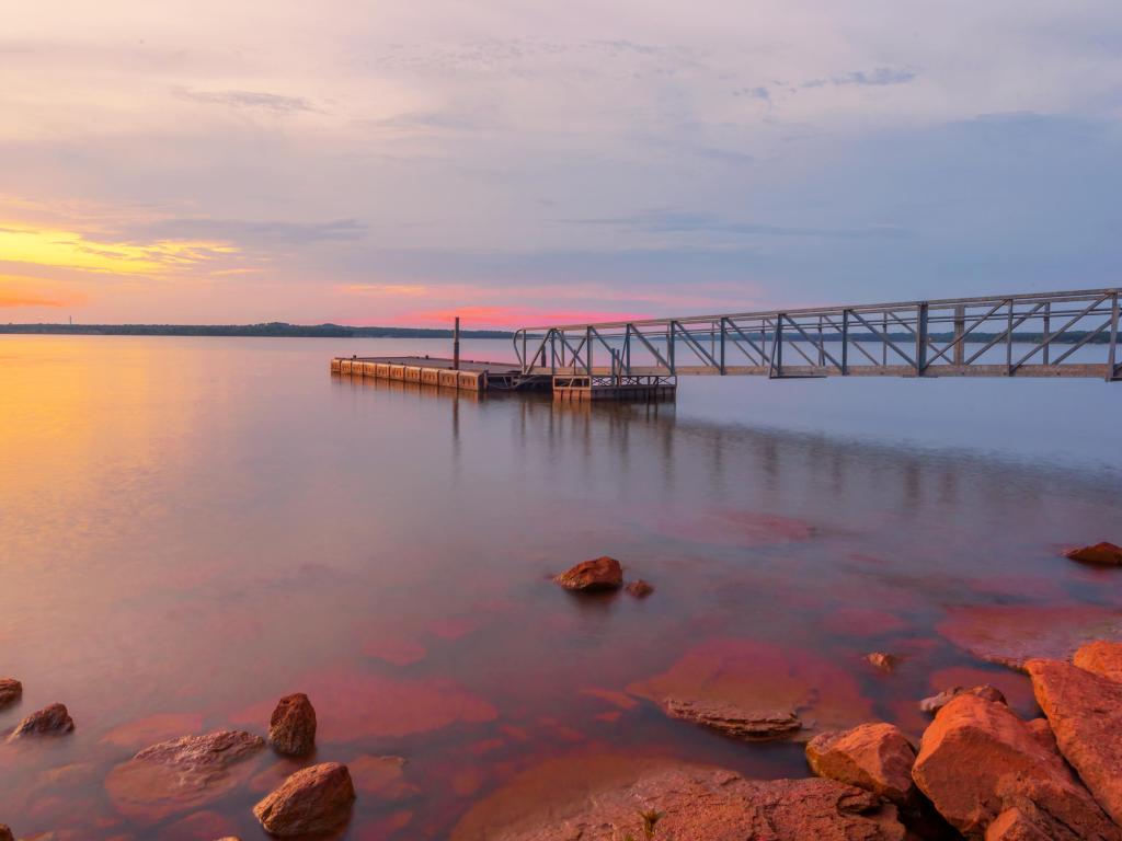 Beautiful sunset over the lake, smooth water and a pier in the background